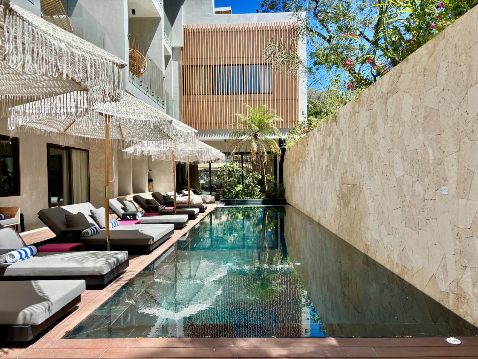 Main saltwater pool with macramé umbrellas and tropical garden wall